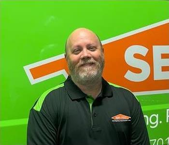 Man with gray hair standing in front of Servpro sign