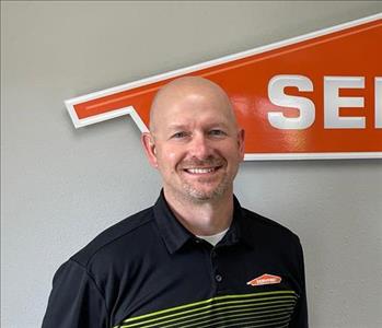 Bald male employee smiling in front of SERVPRO sign