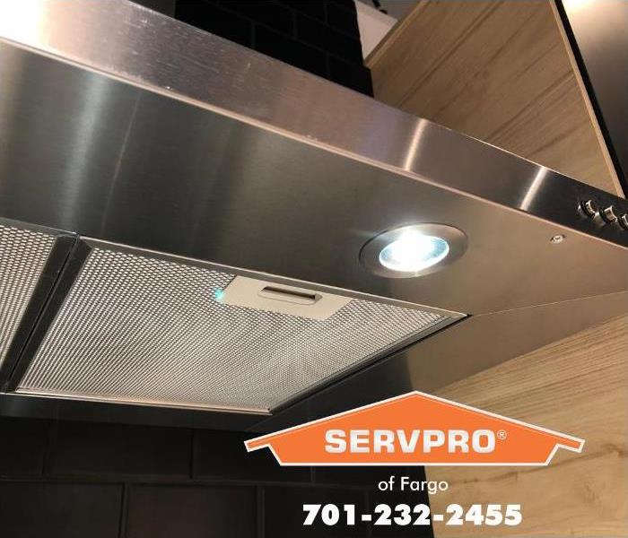 A stainless steel commercial restaurant stove exhaust vent is shown sparkling clean.