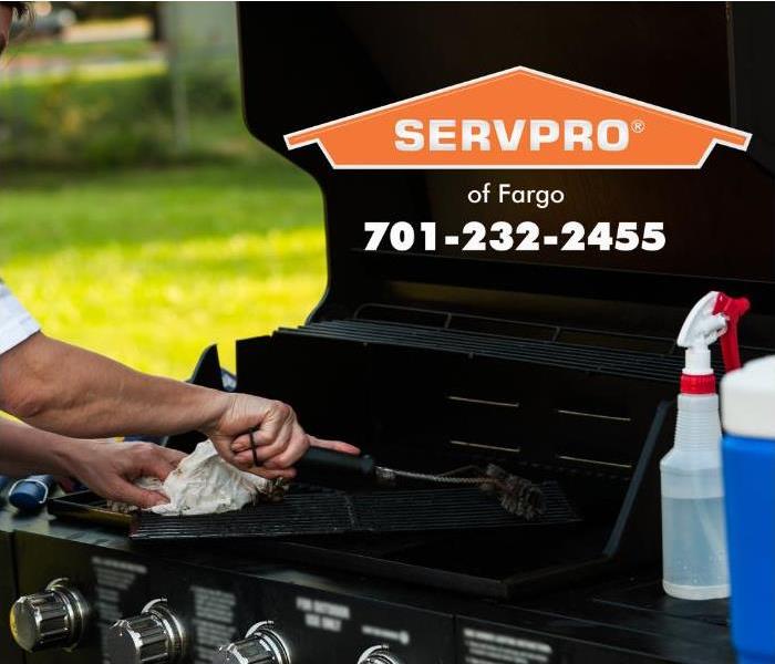 A person is shown cleaning a propane barbeque grill.